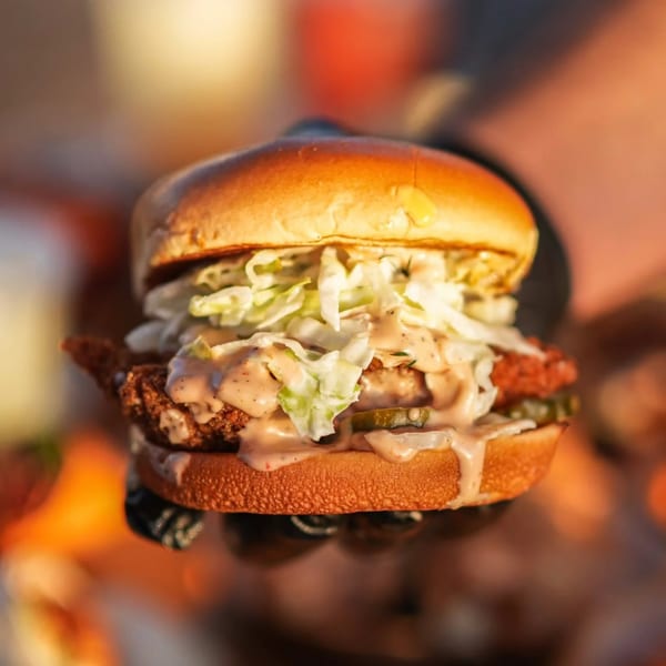 Close-up of a Hot Chicks Food Truck fried chicken sandwich with slaw, pickles, and sauce.