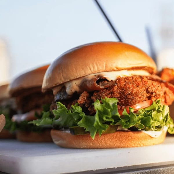 Close-up of a Hot Chicks Food Truck fried chicken sandwich with lettuce, tomato, and pickles.